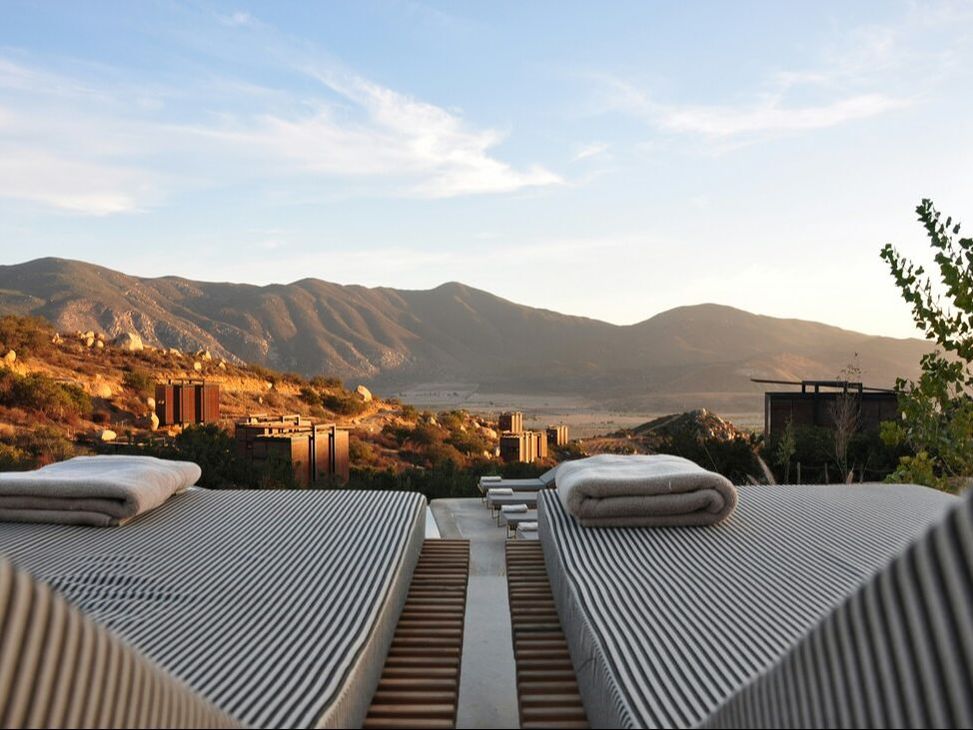 Striped sun loungers overlooking desert mountains at golden hour